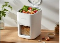 Modern white electric kitchen composter with fresh vegetable scraps inside